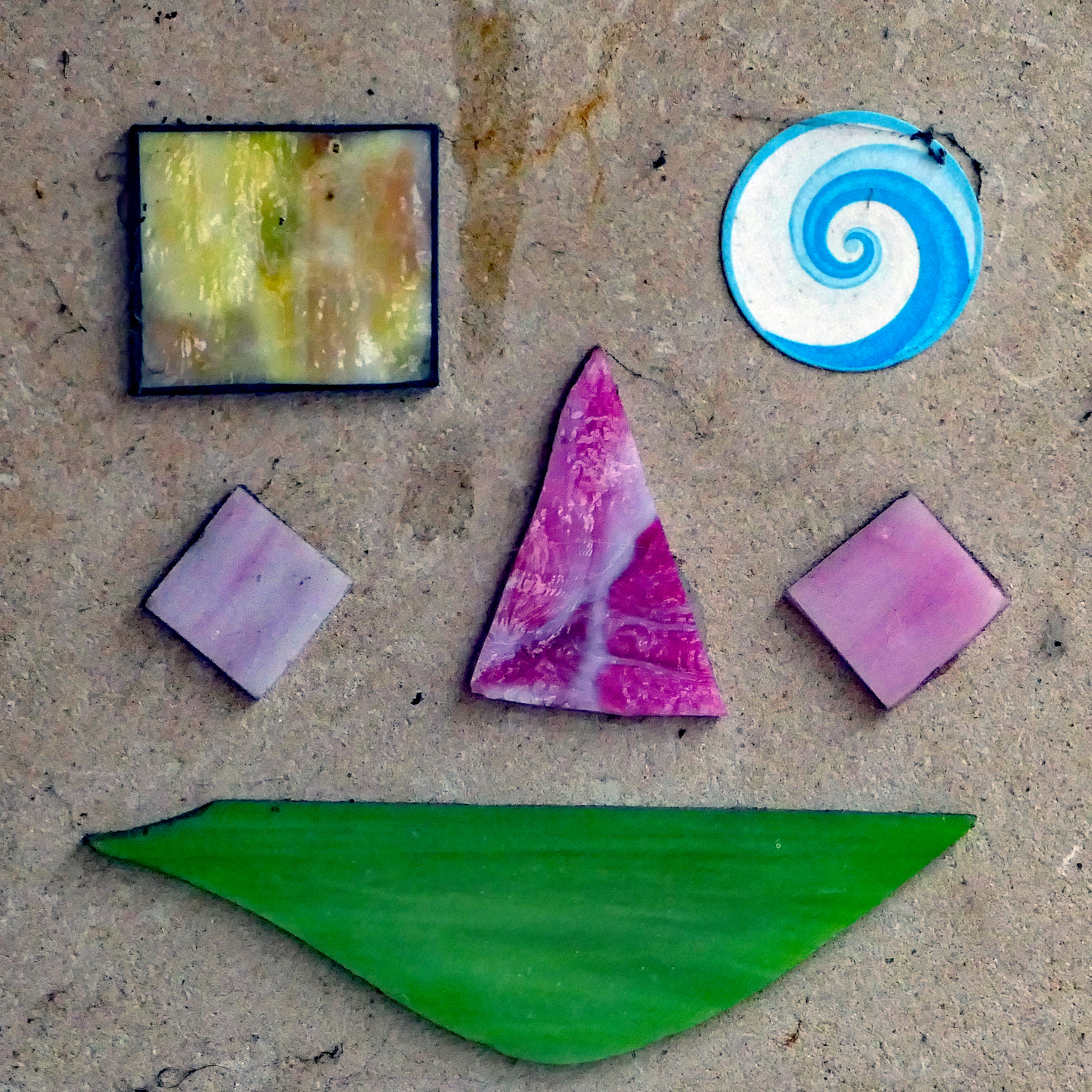 Gesicht aus Glasscherben auf Steinplatte