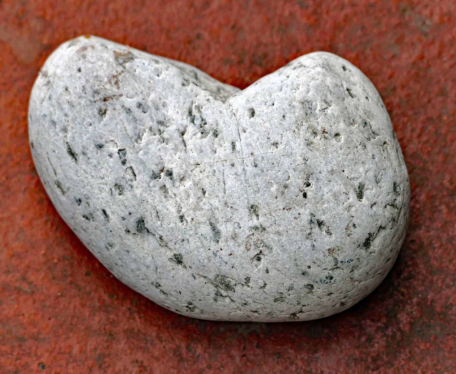 Heller Herz-Stein auf rötlicher Klinkerplatte